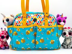 Belle Baby Bag, made by Chanova Alcala Mabry from That's Sew Nova / Nova's Knits in fabric printed with cartoon bees on a blue background and in colourful hexagon fabric, with yellow straps and accents.