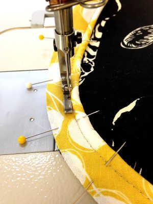 Machine basting yellow and white piping to a black bag panel