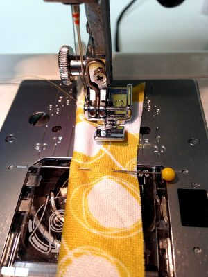 The needle area of a sewing machine with handmade piping ready to stitch